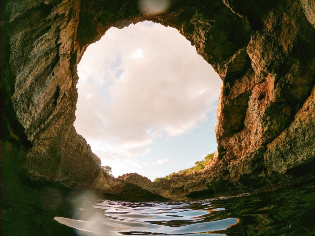 circle of sky with stone cave around and water below