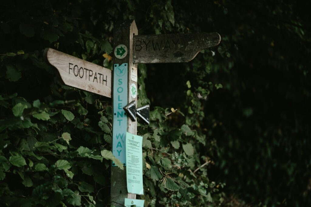 photo by Annie Spratt for Unsplash - sharing forest wooden marker with words footpath - by way - channel - in different directions